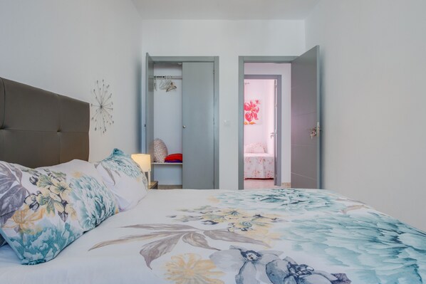 A bedroom with a bed, a wardrobe, and a door leading to another room.