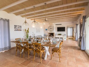 A dining area with a wooden table, wicker chairs, and hanging pendant lights.