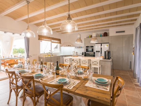 Comedor con una mesa de madera dispuesta para seis personas, rodeado de sillas de mimbre.