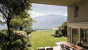 Une terrasse avec une table et des chaises, une pelouse et une vue sur la montagne.