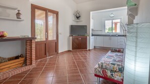 A kitchen with a TV, a wooden cabinet, a tiled floor, and a window. - Beautiful Country House with Pool, Terraces & Wi-Fi; Parking Available (Artá)
