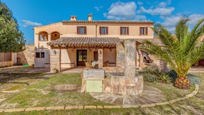 A Mediterranean-style building with a courtyard, stone pillars, and a palm tree. - Holiday Home "Son Galiana" with Wi-Fi, Garden and Terrace (Montuïri)
