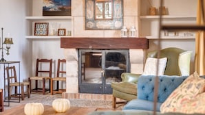 A cozy living room with a fireplace, wooden chairs, a green sofa, and decorative items on shelves. - Holiday Home "Son Galiana" with Wi-Fi, Garden and Terrace (Montuïri)