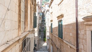 A narrow street with stone buildings, a staircase, and a person descending. - Apartment Old Writer (Dubrovnik)