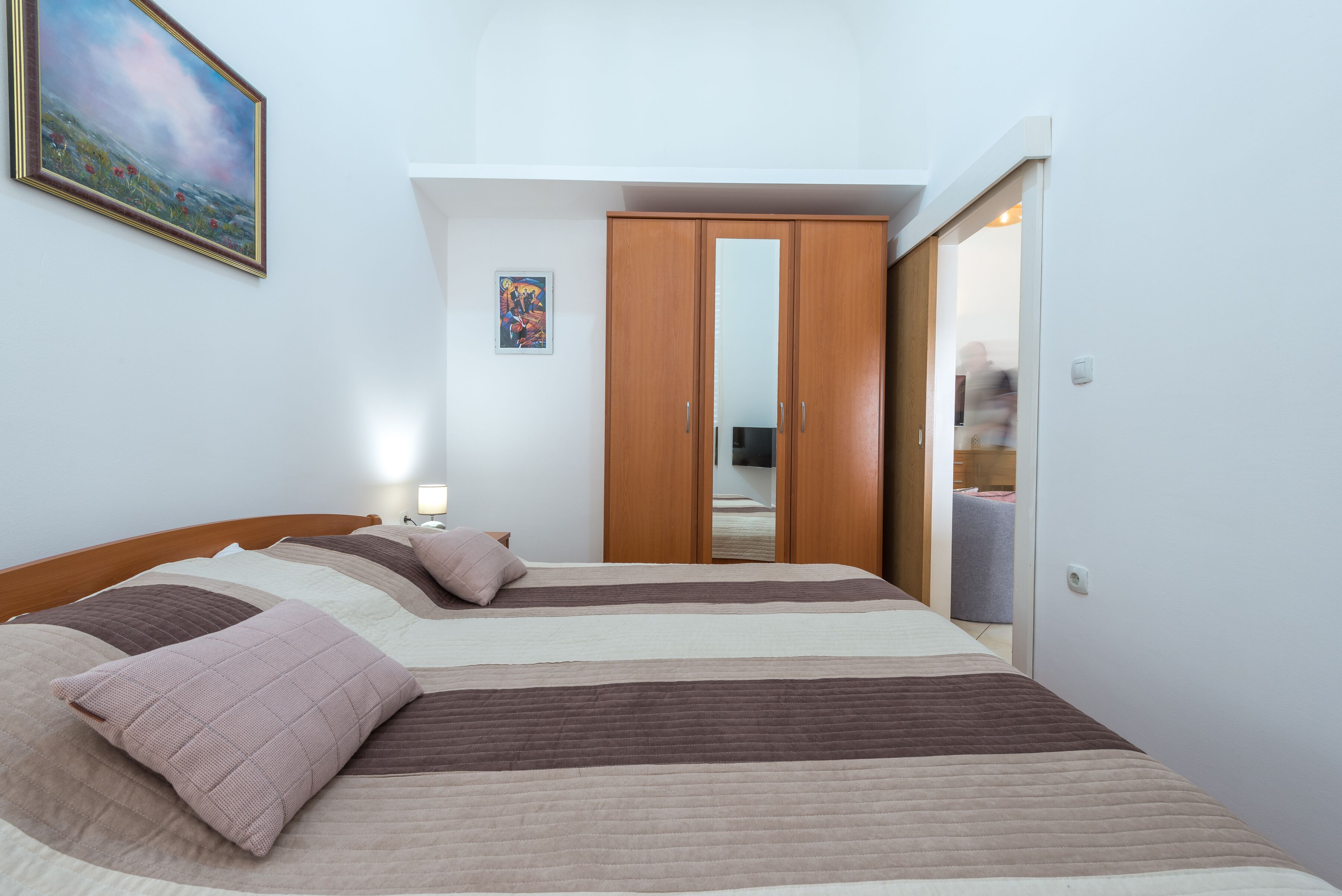 A bedroom with a large bed, a wardrobe, and a mirror.