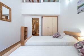 Un dormitorio con dos camas, un armario, un espejo y una puerta que da al baño.