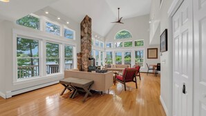 Un salón espacioso con chimenea de piedra, ventanas amplias y comedor.