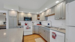 Una cocina moderna con gabinetes blancos, un microondas, una estufa y un lavamanos.