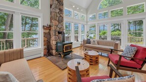 Un salón amplio con chimenea de piedra, ventanas grandes y una zona de estar acogedora.