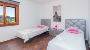 Une chambre avec deux lits, une table de chevet, une lampe et une image de la Tour Eiffel.