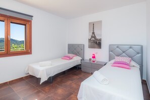 A room with two beds, a nightstand, a lamp, and a picture of the Eiffel Tower.