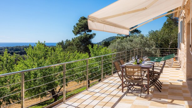 Une terrasse avec une table dressée pour le repas, un auvent et une vue sur le paysage.