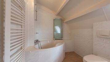 Un baño con bañera, inodoro y cabina de ducha de vidrio.