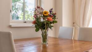 Un jarrón de cristal transparente con una variedad de flores sobre una mesa de madera.