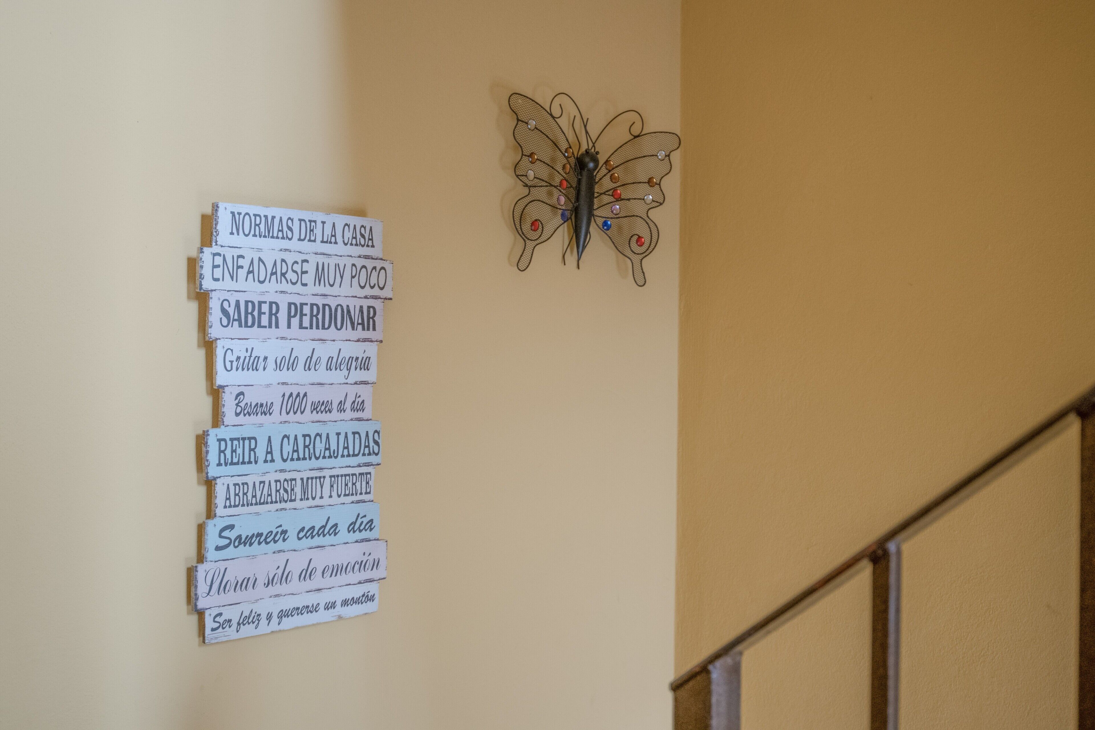 A wall with a butterfly decoration and a series of signs with motivational phrases in Spanish.