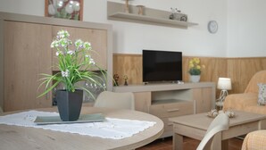 A modern living room with a round wooden table, a potted plant, a flat-screen TV, and a sofa. - Family Friendly Apartment "Rocio" with Terrace, Air Conditioning and Wi-Fi (Conil de la frontera)