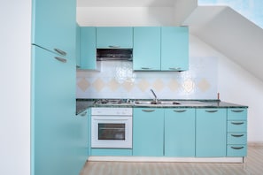 Una cocina con gabinetes color turquesa, una estufa blanca y un salpicadero de azulejos.