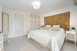Une chambre à coucher comprenant un lit, des tables de chevet, une commode, une chaise, une porte et un mur orné d’un motif texturé.