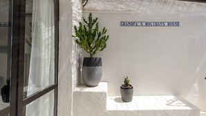 A potted plant and a sign reading 'Grandpa's Holidays House' on a white wall. - Holiday Home "Casita en Cala Llonga" with Sea View, Shared Garden & Pool (Cala Llonga)