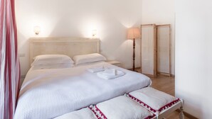 A bedroom with a bed, bedside lamps, a nightstand, and a mirror.