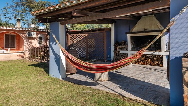 Un hamac dans un espace patio, avec un barbecue et une clôture en bois.
