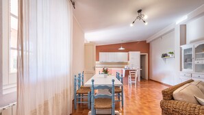 Un coin repas avec une table et des chaises, une cuisine en arrière-plan et un canapé en osier.
