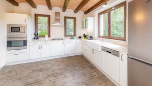 Una cocina moderna con armarios blancos, un refrigerador de acero inoxidable y pisos de madera.