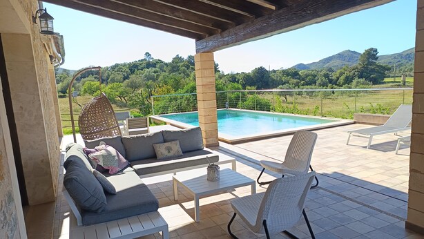 An outdoor patio with a pool, a sofa, a chair, and a table.