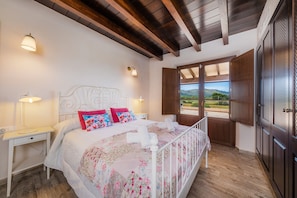 Una camera da letto con un letto, comodini, una finestra vista e travi in legno al soffitto.