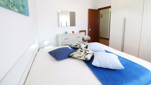 Een slaapkamer met een bed, een kaptafel, een spiegel en een kledingkast.