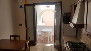 Une cuisine équipée d’une cuisinière, une table à manger avec des chaises et un balcon avec une table et des chaises.