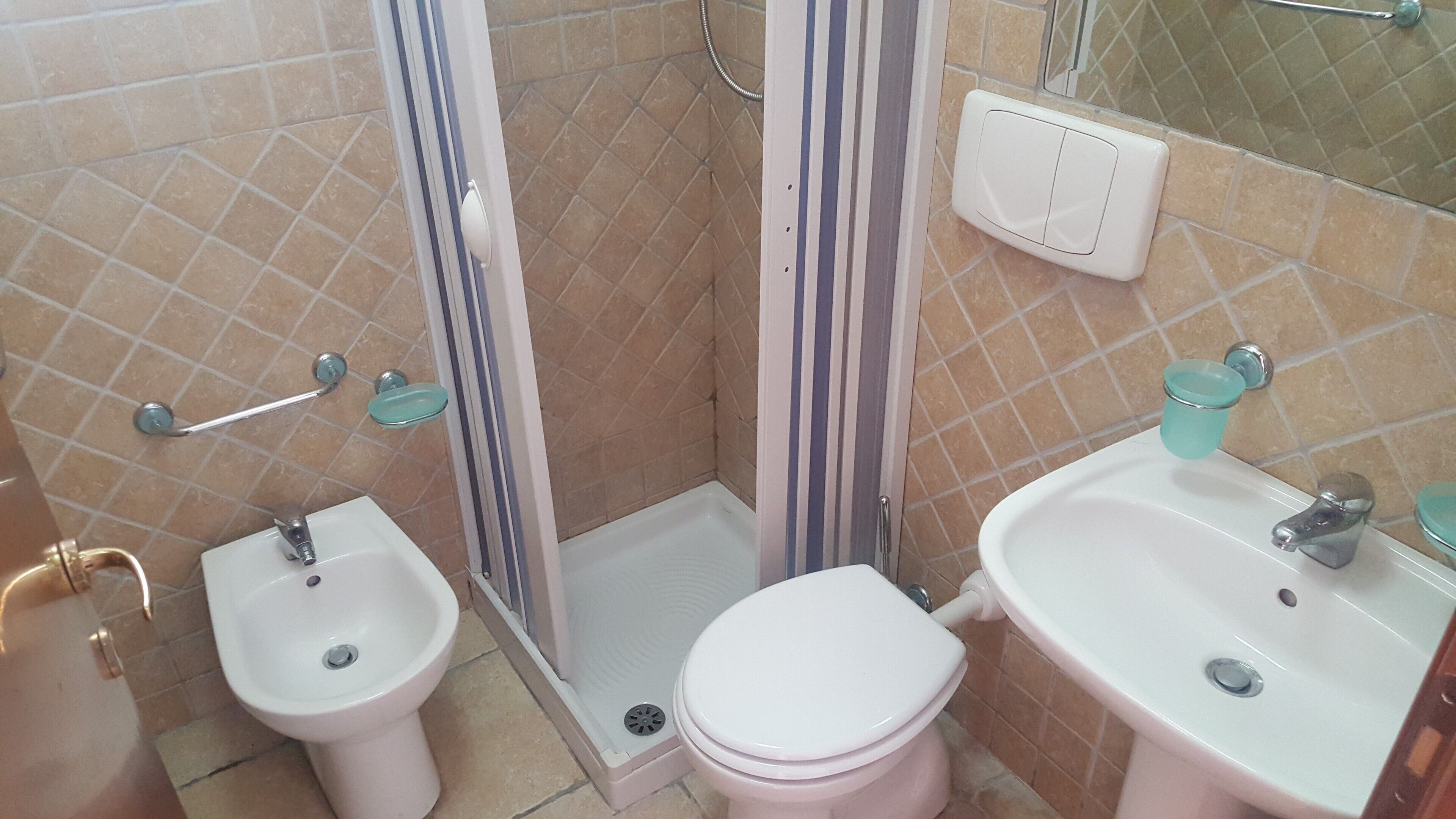 A bathroom with a shower, bidet, toilet, and sink.
