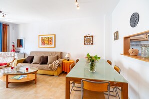 A living room with a sofa, coffee table, and dining table.