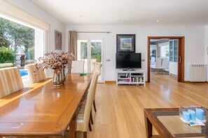 Un salon spacieux avec une table à manger en bois, un téléviseur à écran plat et une bibliothèque.