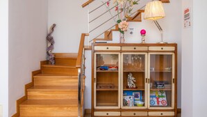 A wooden staircase leading to a landing with a vintage cabinet containing glassware and toys. - House with Mountain Views, Pool, Garden, Terrace, A/C and Wi-Fi (Cala d'Or)