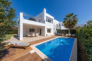 Une maison moderne à deux étages dotée d’une piscine, de mobilier d’extérieur et d’un espace patio.