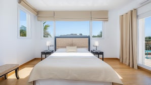 A bedroom with a large bed, two bedside tables, a bench, and a view of the outdoors. - House with Mountain Views, Pool, Garden, Terrace, A/C and Wi-Fi (Cala d'Or)