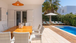 A patio with a dining table, chairs, and a pool area with lounge chairs and an umbrella. - House with Mountain Views, Pool, Garden, Terrace, A/C and Wi-Fi (Cala d'Or)