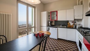 A kitchen with a view, white cabinets, a red-framed cabinet, a stove, and a window.