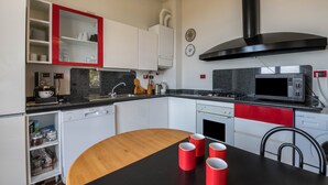 A modern kitchen with white cabinets, a black countertop, and a red accent wall.