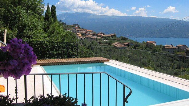 A swimming pool with a view of a lake and mountains in the background.