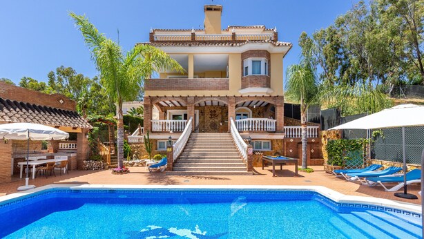 Une maison à deux étages dotée d’une piscine, d’un espace extérieur aménagé et d’un escalier menant à l’entrée.