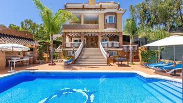 Une maison à deux étages dotée d’une piscine, d’un espace extérieur aménagé et d’un escalier menant à l’entrée.