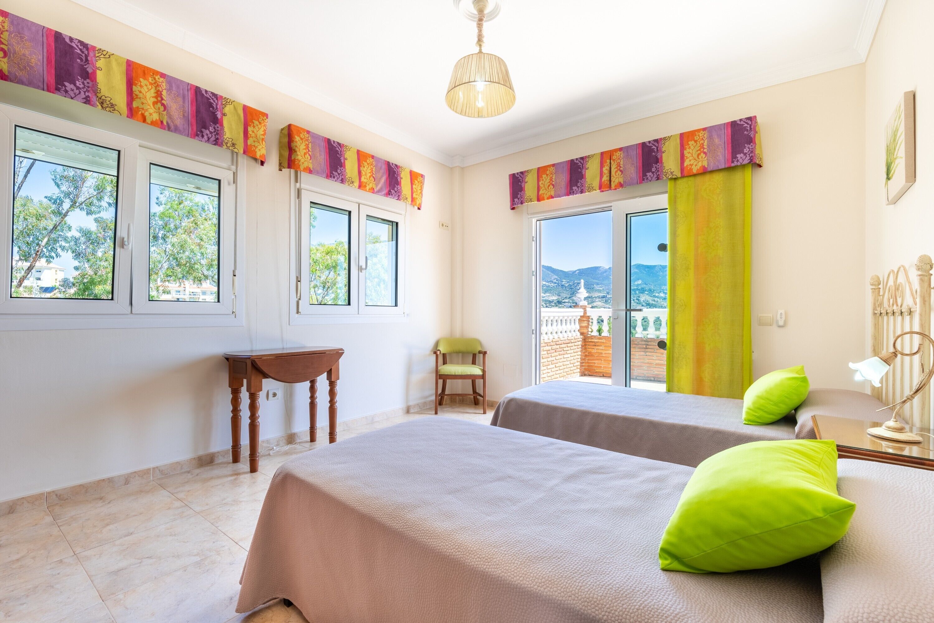 Une chambre avec deux lits, une chaise, une table et une vue sur l’extérieur.