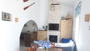 Un comedor amplio con una mesa y sillas de madera, un florero con flores y una cocina al fondo.