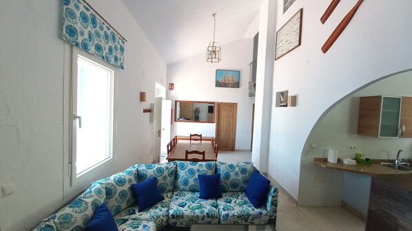 A modern interior with a sofa, dining table, and kitchen area.