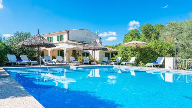 A swimming pool with lounge chairs and umbrellas, surrounded by a building with green shutters. - Villa "Son Perxa" with Pool and Garden (Petra)