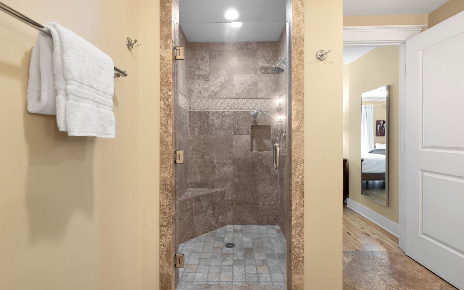 A walk-in shower with a glass door, a towel rack, and a showerhead.