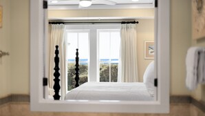Een slaapkamer met een bed, een plafondventilator en uitzicht op het omliggende landschap.