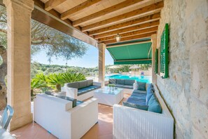 Un patio al aire libre con mobiliario de mimbre, una piscina y vistas del paisaje.